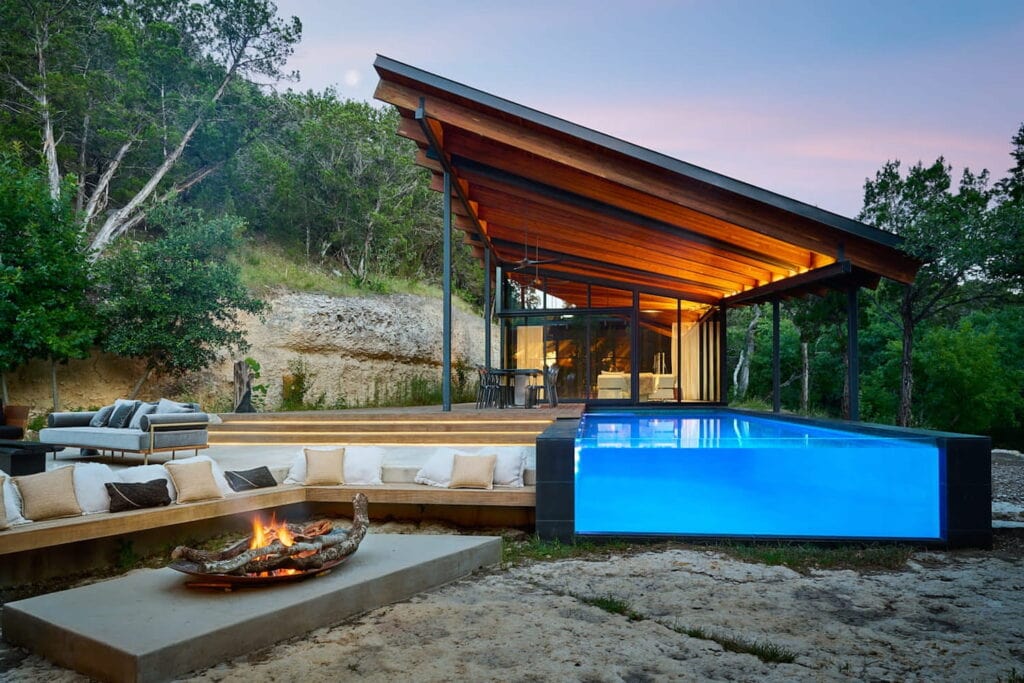 Backyard space of glass house in Austin with pool and built in seating