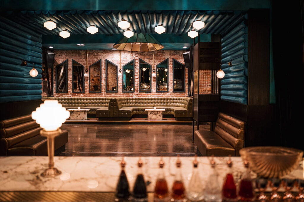 Art deco bar space with brick walls, gold banquets, and marble countertops