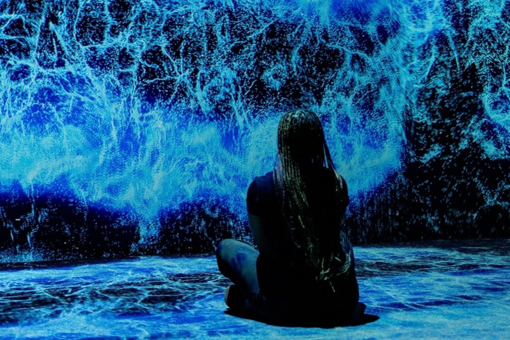 A woman sits on the floor experiencing an immersive moment at Arte Museum in New York