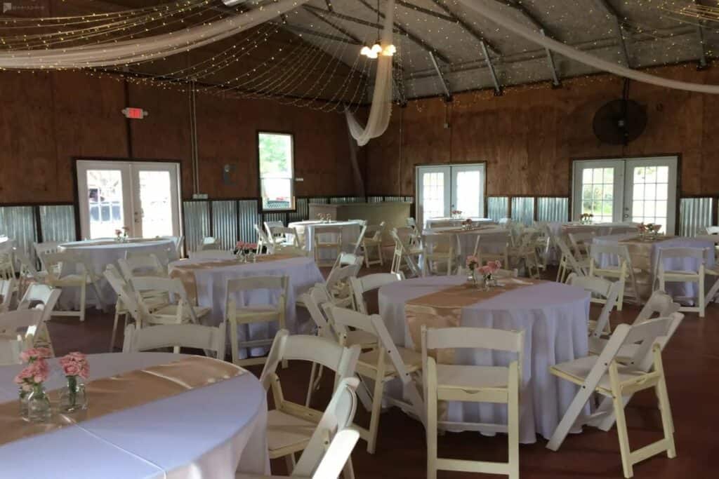 a rustic banquet hall with string lights and white tables