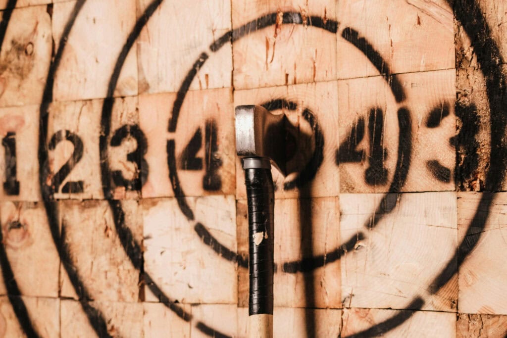 An axe sits at the bullseye on hatchet throwing board.