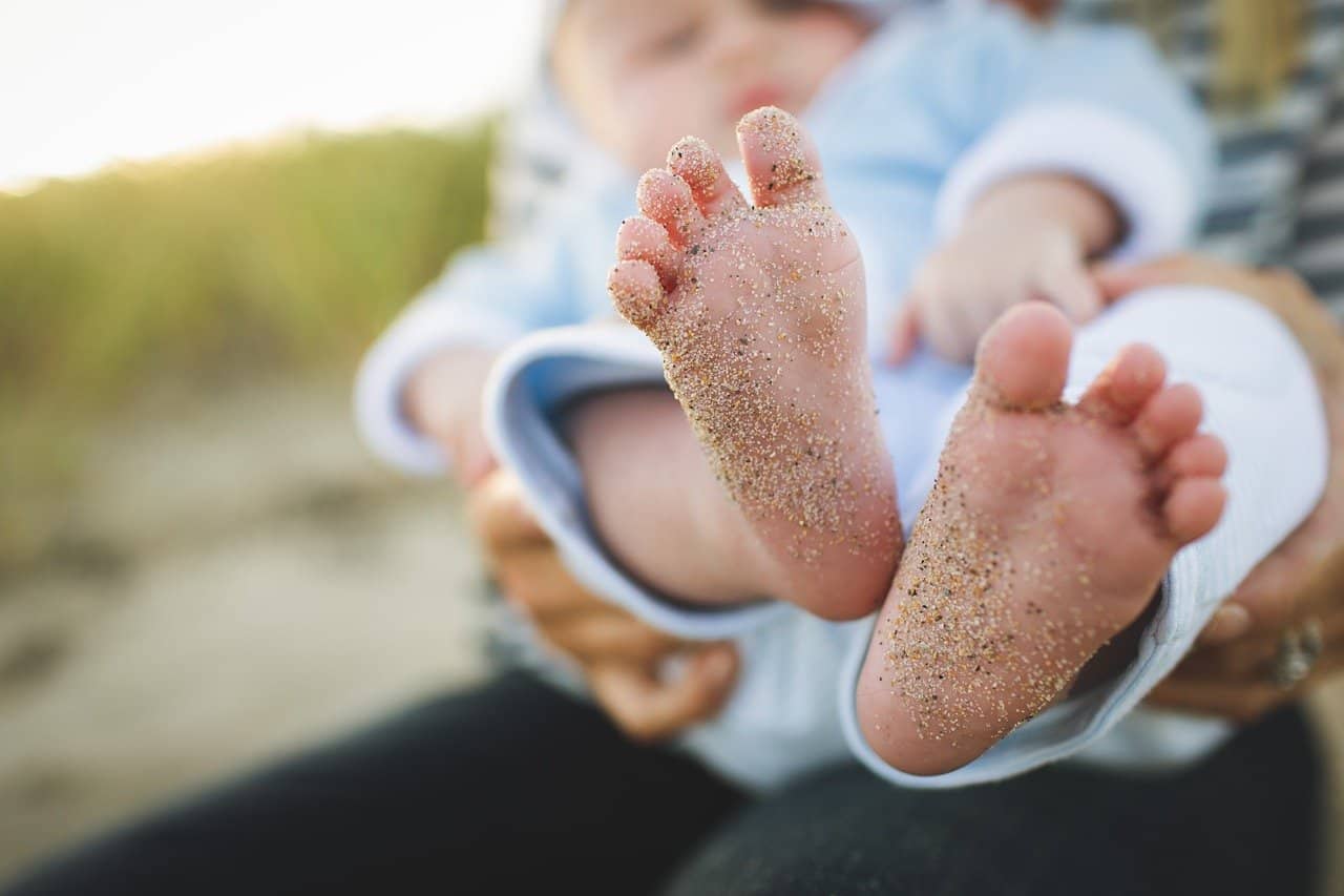 baby feet covered in sand