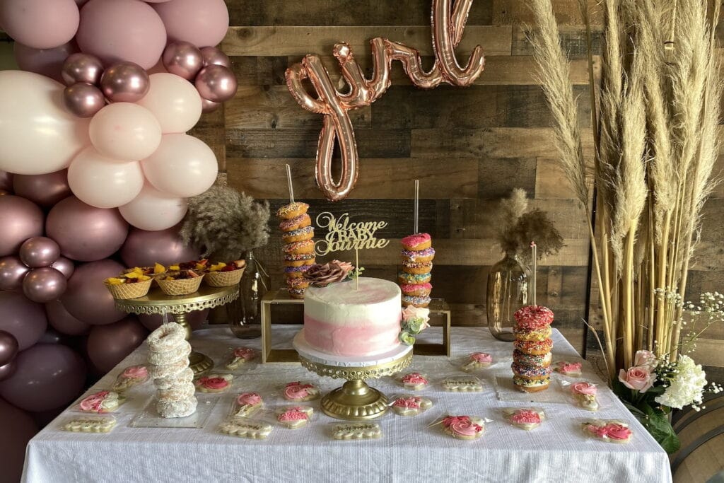 Dessert table at a girl-themed baby event with pink balloons