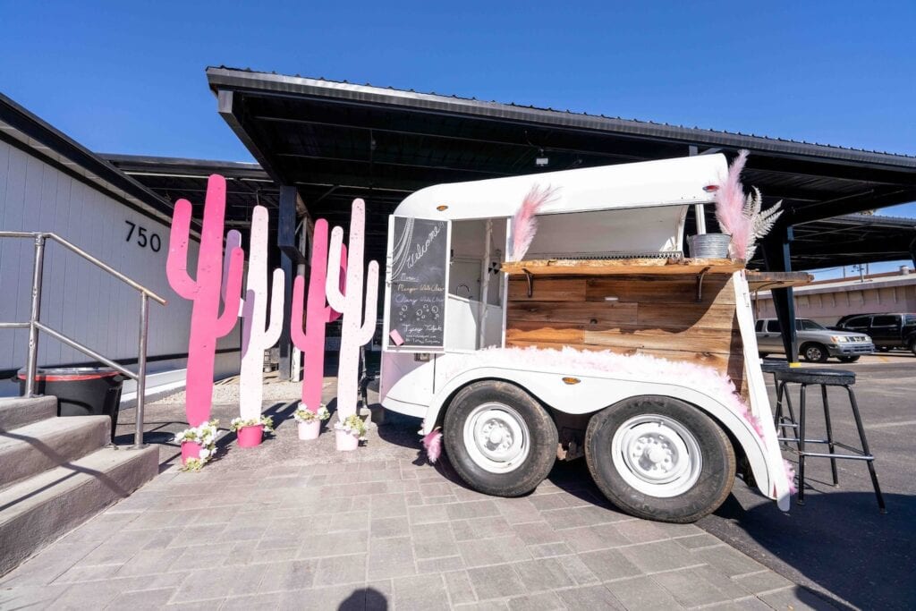 Bar cart sitting outside at a venue next to pink and white cutout cactuses