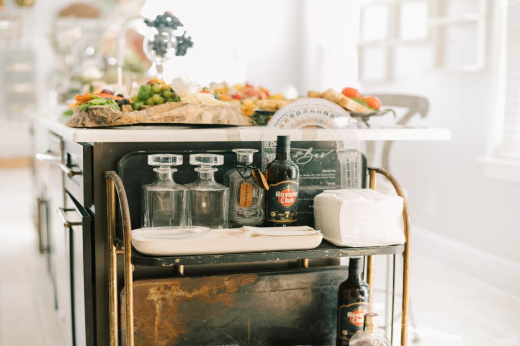 A bar cart sits at the end of a kitchen island full of appetizers