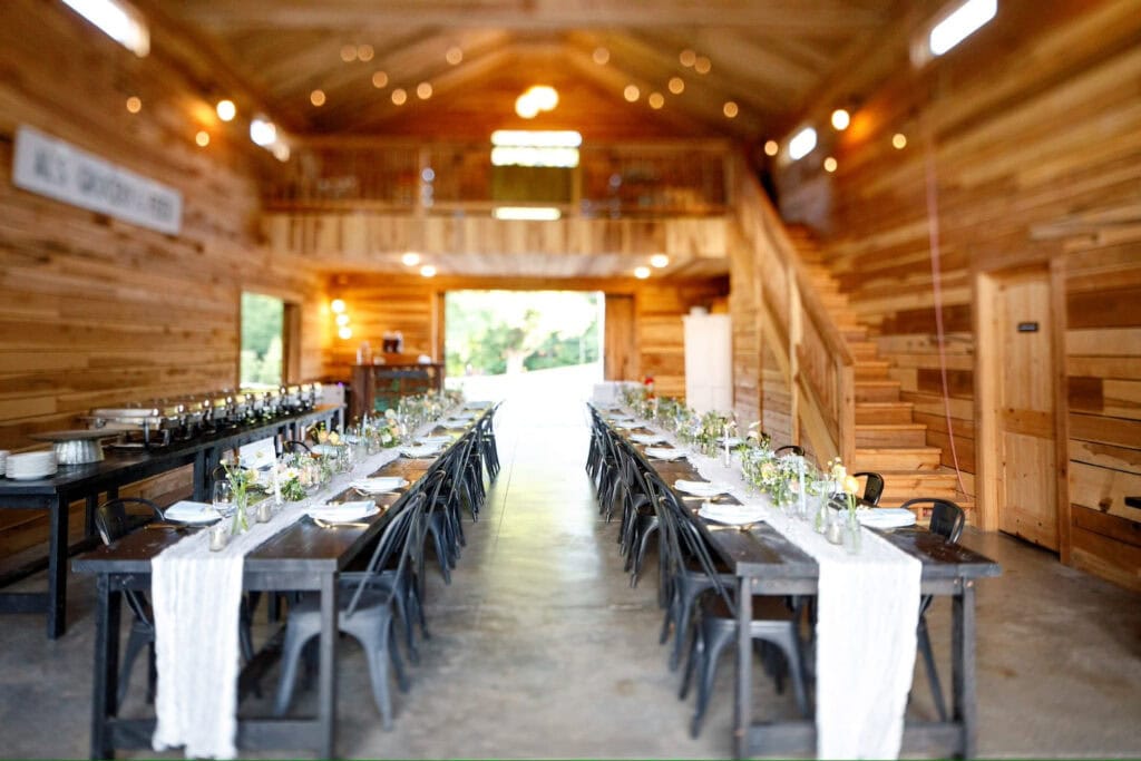 Long, dark guest tables are set up inside a wooden barn