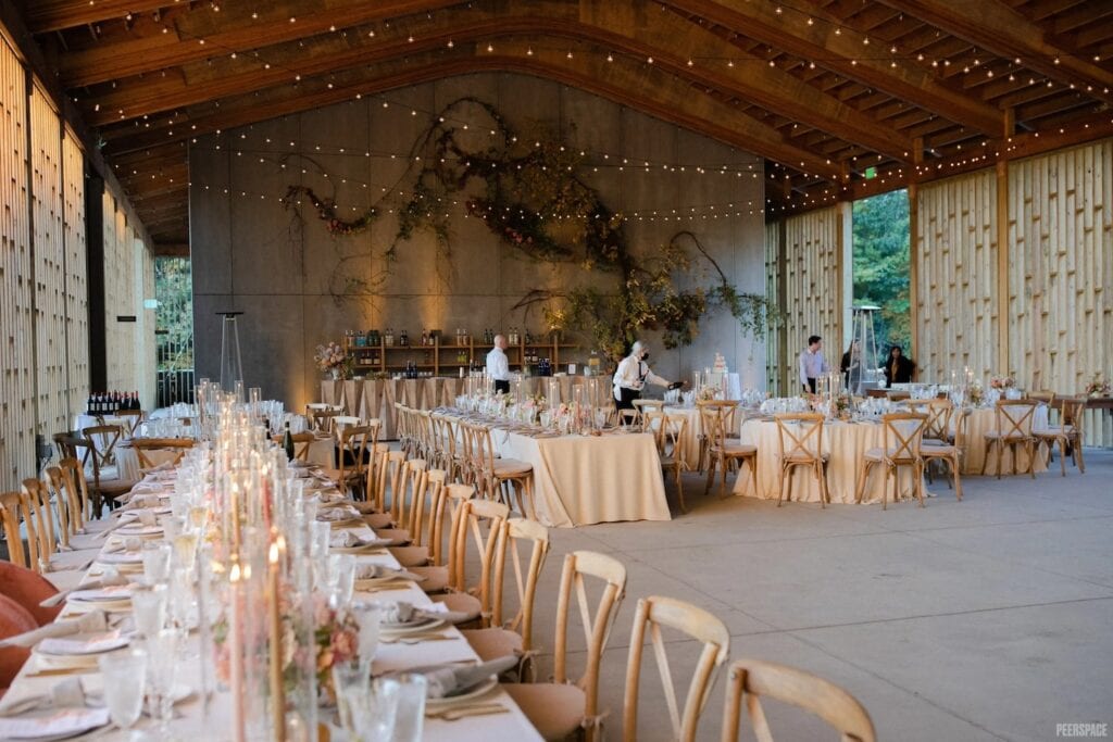 Tall ceilings punctuate a large, open reception space decorated with string lights and simply-decorated guest tables