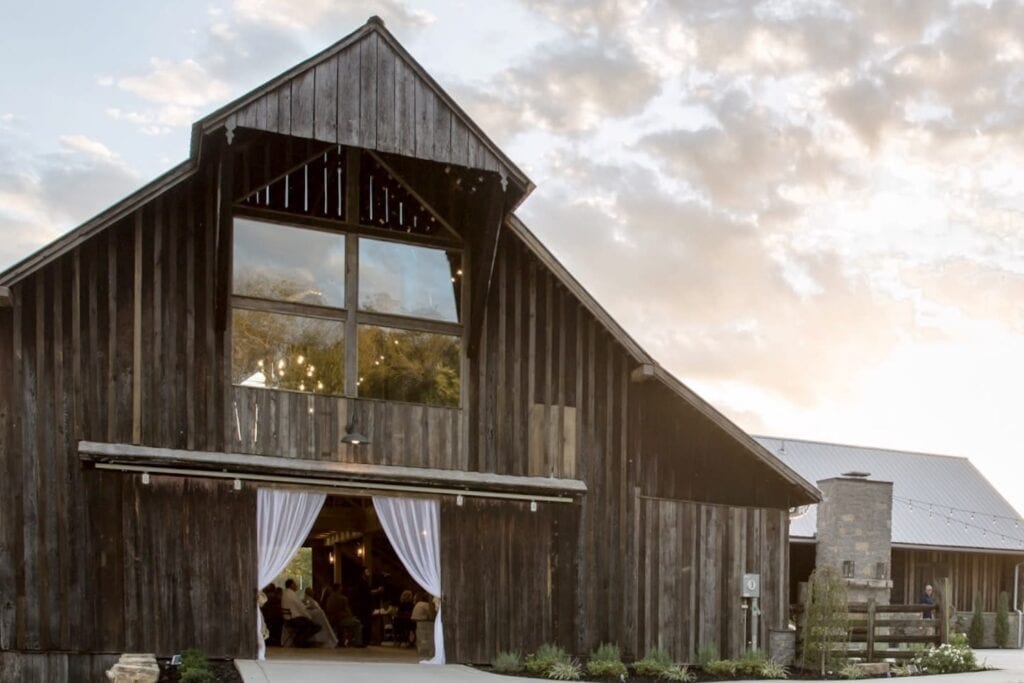 White drapes flank the opening to a reception area in a wooden barn