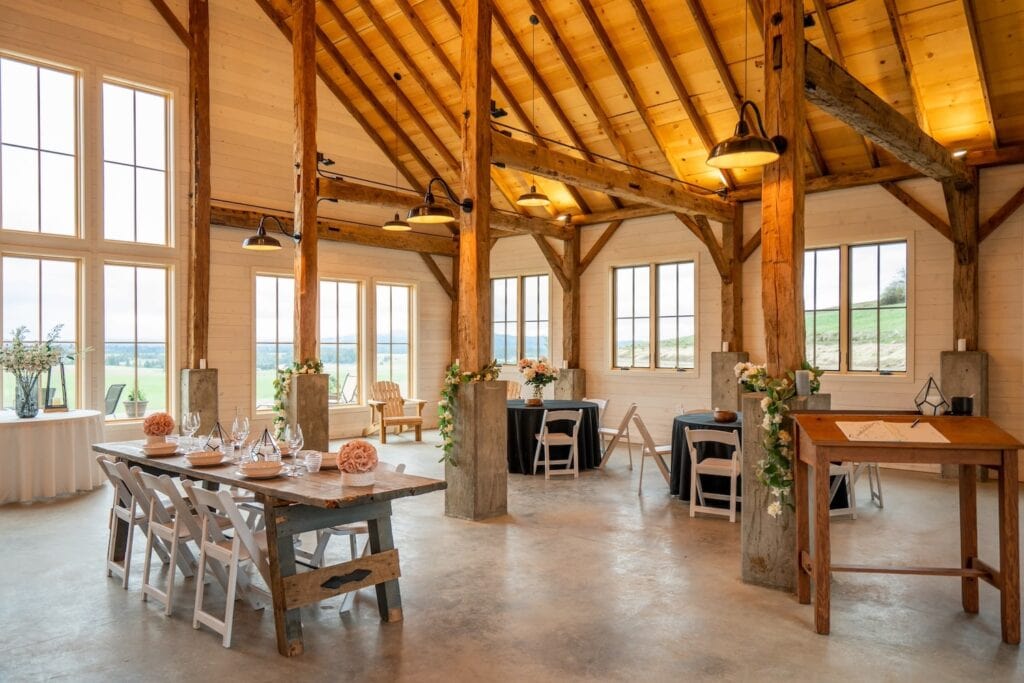Bright barn-style reception space with huge windows looking out at rolling hills and wooden beam accents