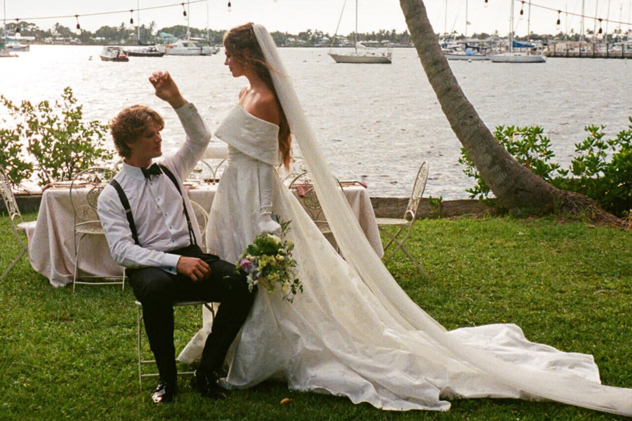 Wedding couple seated on Miami waterfront lawn with sailboats