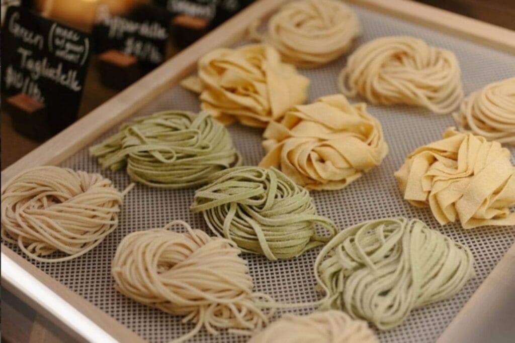 A tray of different colored piles of fresh-made pasta