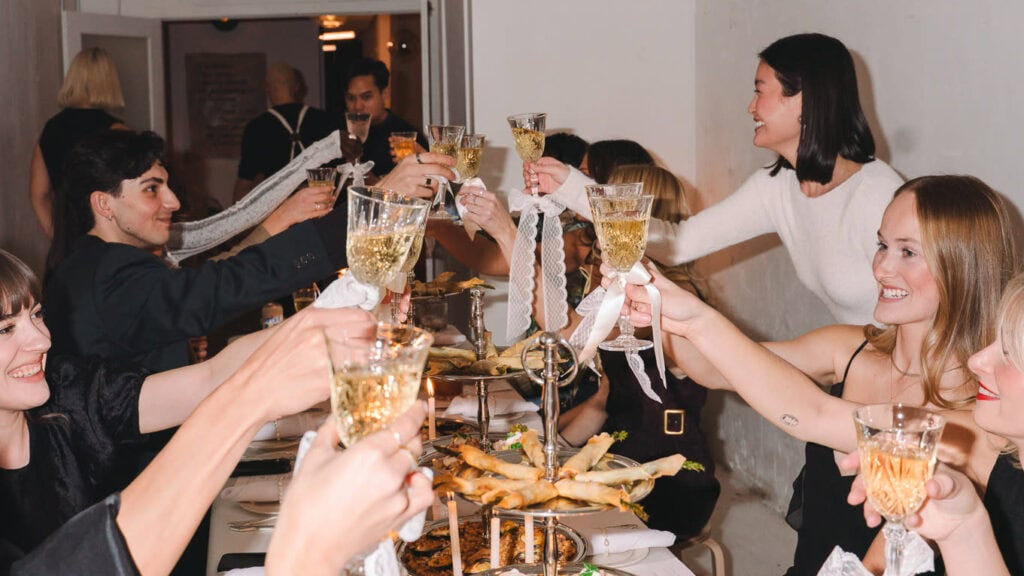 a group of friends gathered around a birthday party touching glasses together for a cheers