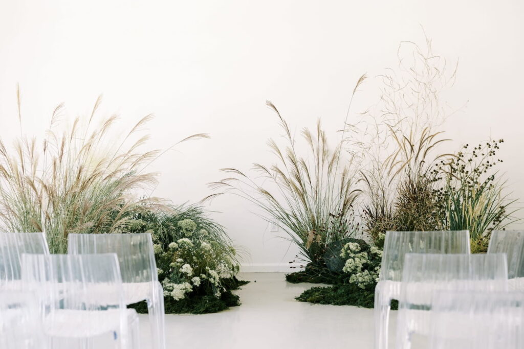 Wedding ceremony set up inside a white room with clear chairs and bohemian floral arrangements set by the altar