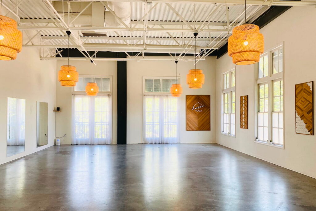Bohemian-inspired dance space with white walls, bright windows and doors, wood and natural accents, and tall ceilings