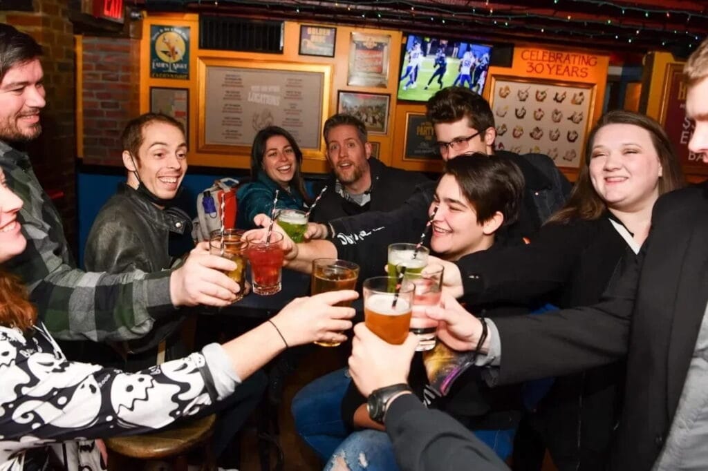 Patrons of a haunted pub crawl toast with beverages inside a pub