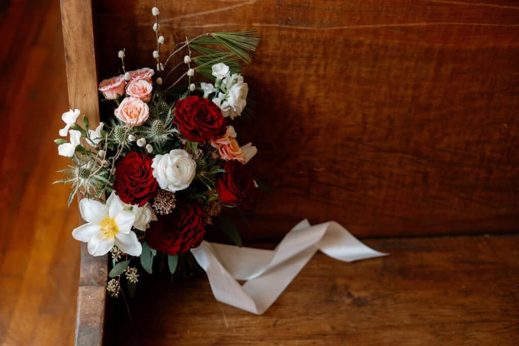 A wedding bouquet sits on a pew in a wedding ceremony venue