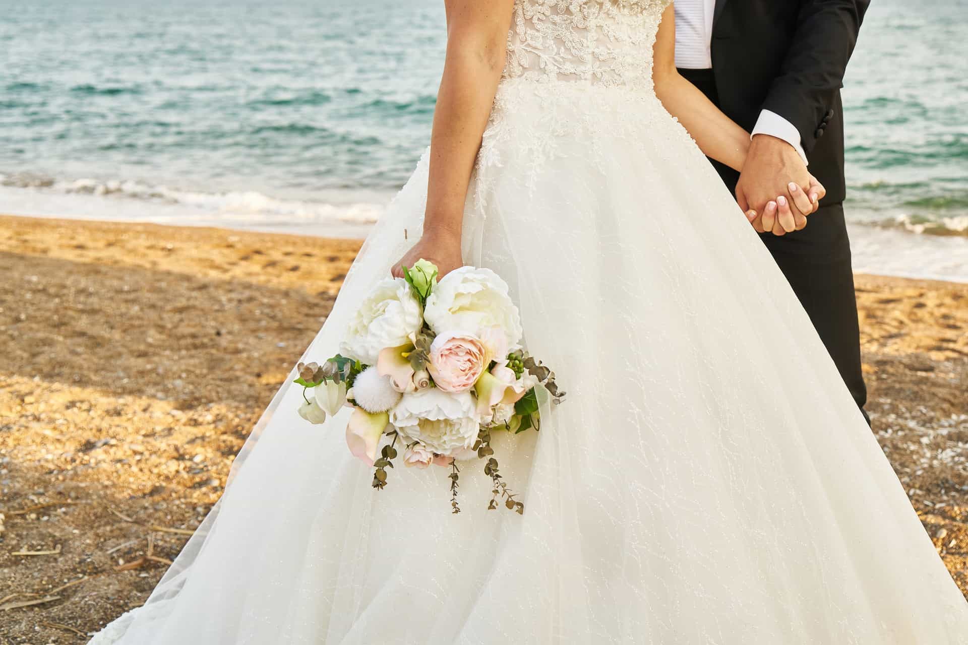 bride and groom holding hands on beach