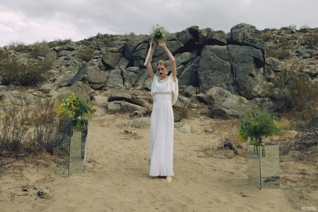 A bride stands at an alter in the desert surrounded by rock and sand