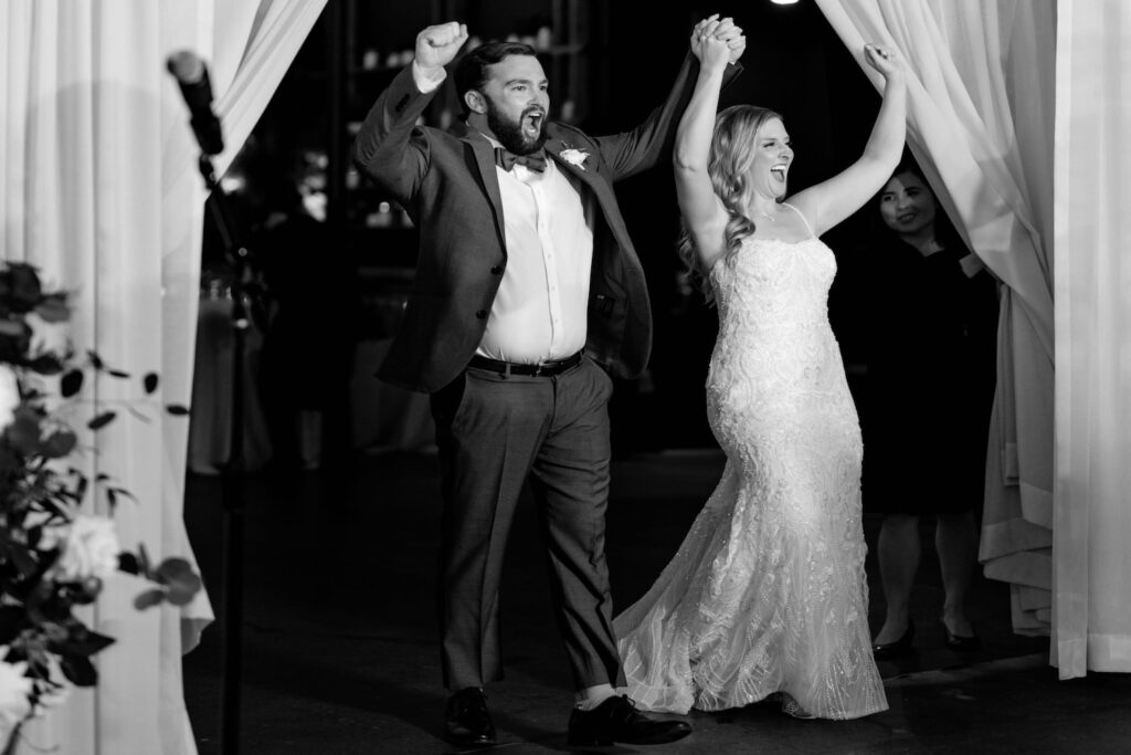 A bride and groom cheer as they make their grand entrance in front of friends and family