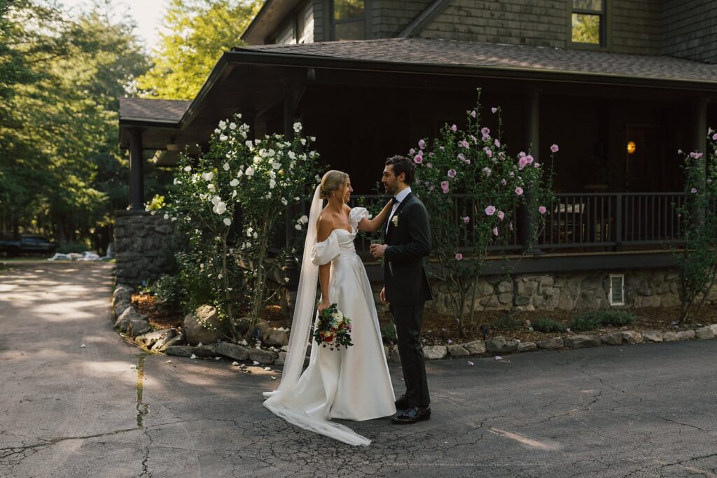 A bride and groom steal a moment outside a rustic mansion in the woods