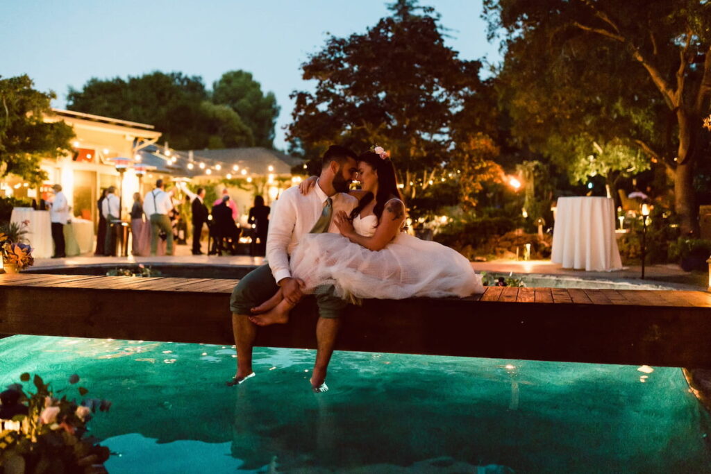 A bride and groom steal a private moment at an outdoor reception by a pool