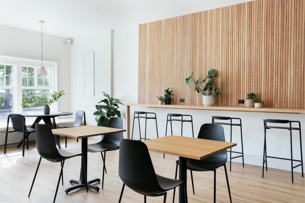 Bright white multi-use office space with multiple seating arrangements, decorated in light wood and black accents
