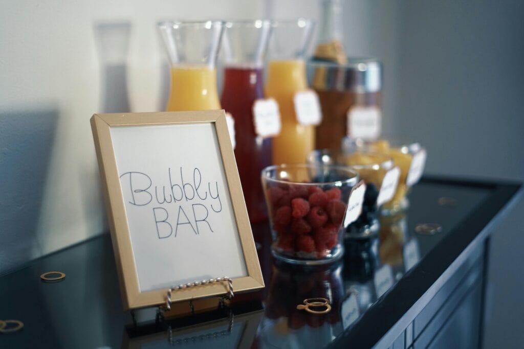 Champagne and mixers sit atop a bar with fruit garnishes