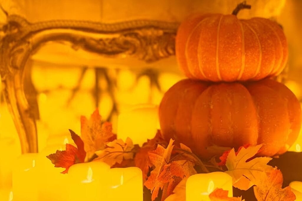Pumpkins and other fall decor are surrounded by candles