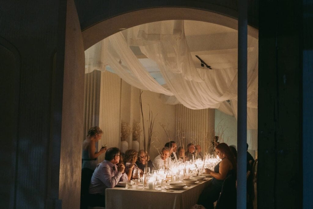 A small group gathers around a candlelit table for dinner