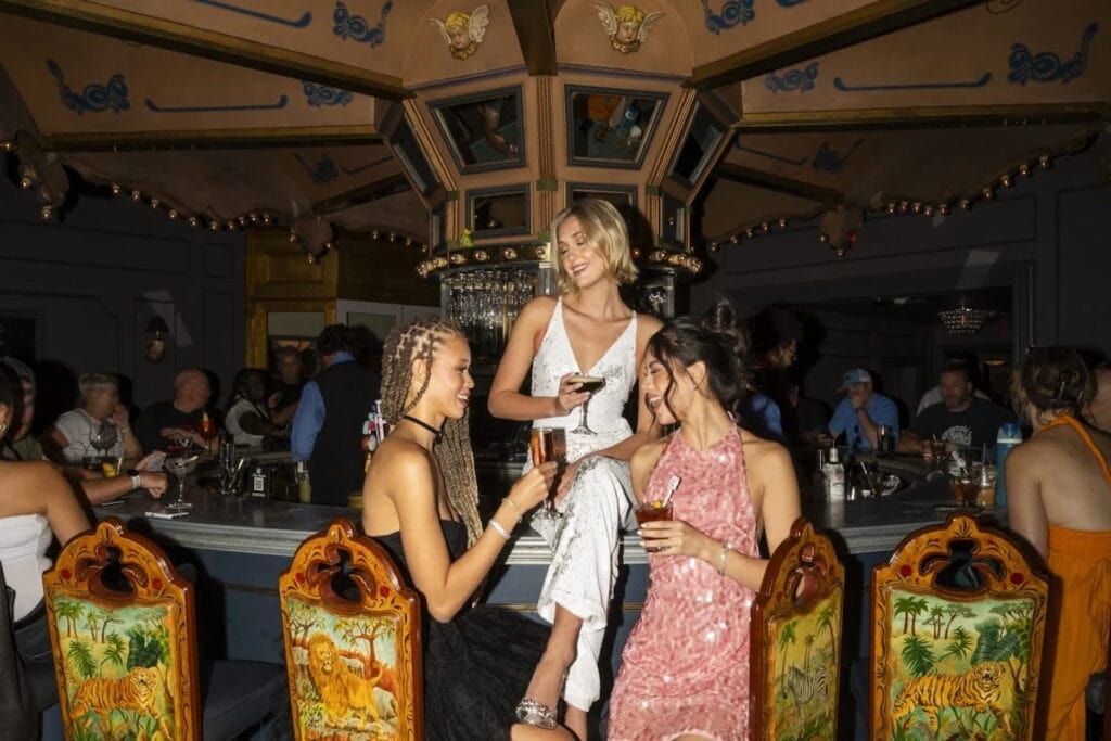 Three women share drinks at a bar shaped like a carousel
