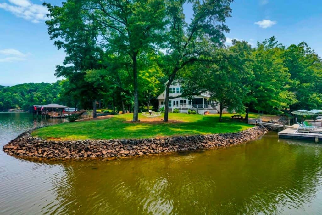 The backyard of a rental house featuring a waterfront area, trees, and adock