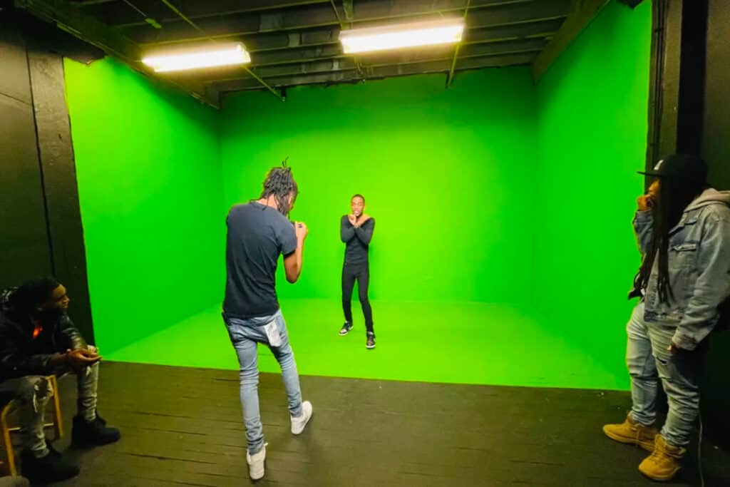 A green screen studio space with people filming a production