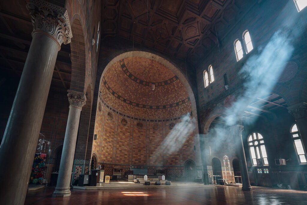 A church-turned-event-space with dark walls, super tall ceilings, soaring columns and a moody vibe