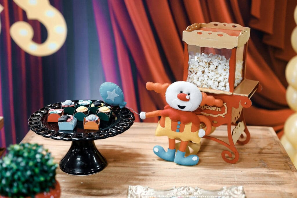 A mini popcorn maker and a clown decorate a circus-themed dessert table