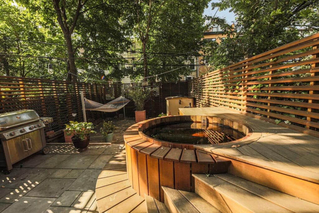 Small, round hot tub built into deck in city backyard