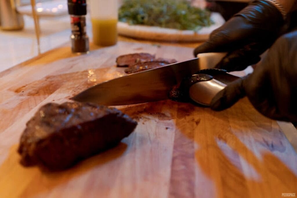 A cut of meat is sliced on a wooden cutting board