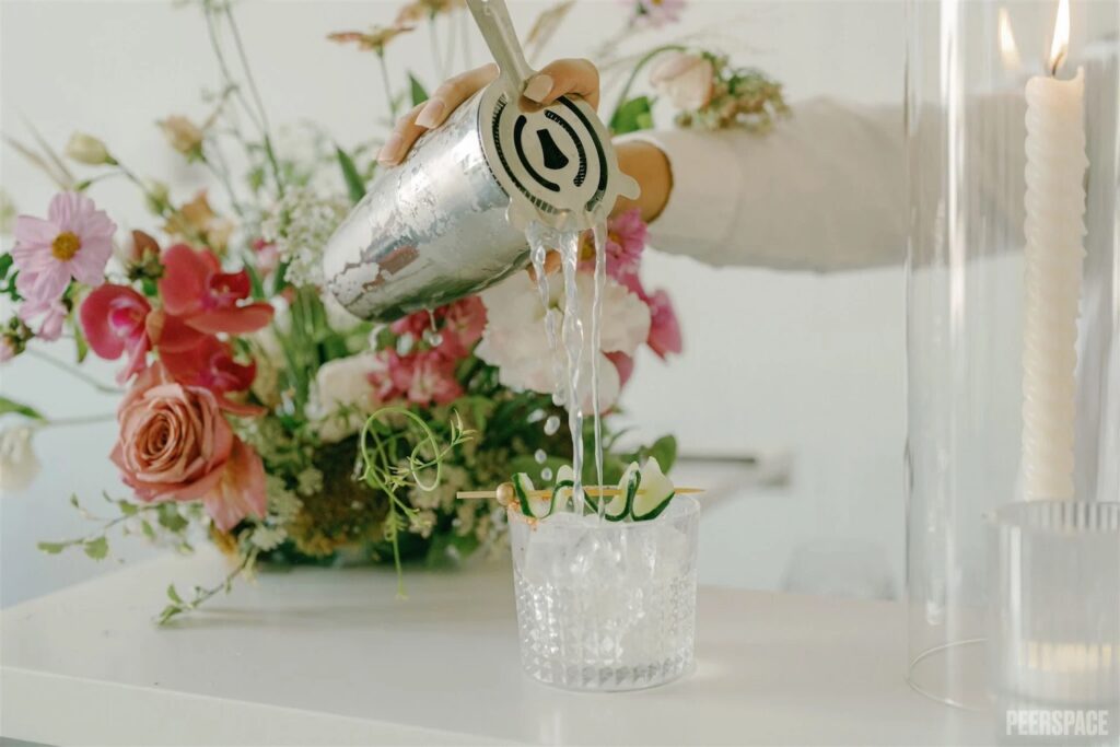 A woman pours a cocktail from a shaker into a crystal glass