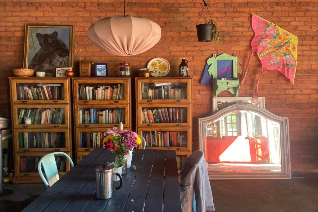 Colorful art, wooden cabinets full of books and interesting decor fill an event space with exposed brick walls