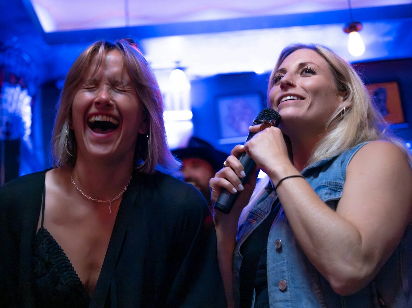 Two friends singing karaoke at an indoor birthday party
