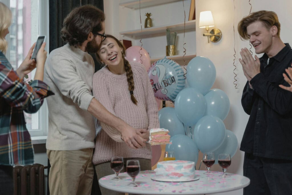 Couple holds up slice of gender reveal cake while onlookers celebrate
