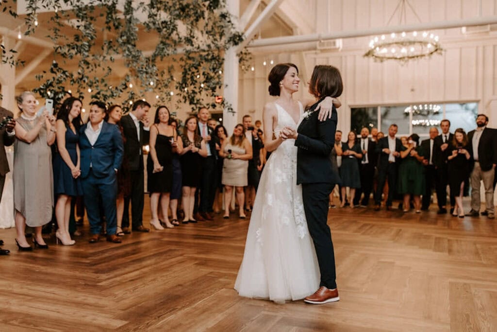 A newly-married couple shares their first dance surrounded by friends and family