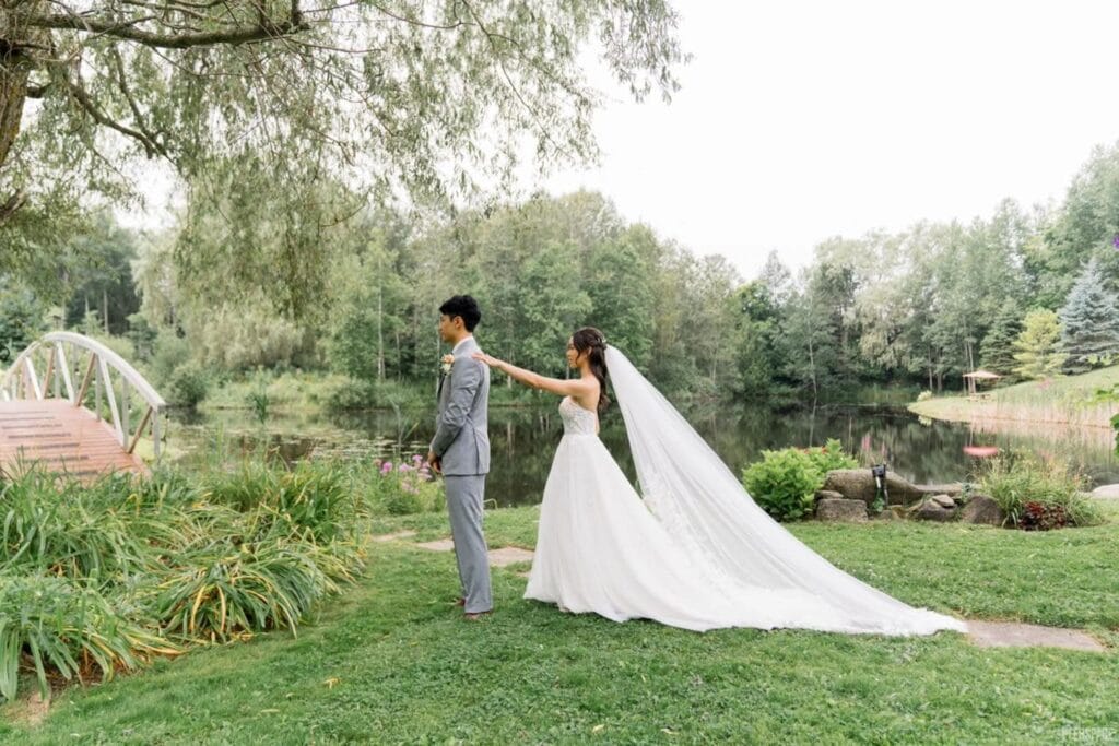 A bride touches the shoulder of her groom for a first look in a garden setting