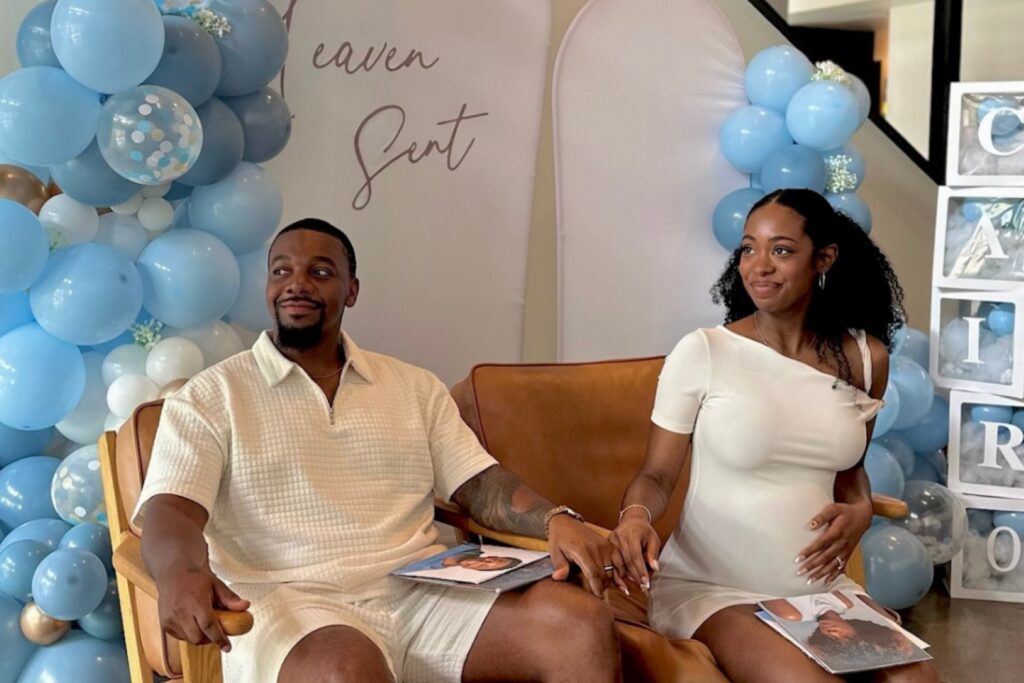 a couple sitting in front of gender reveal signage