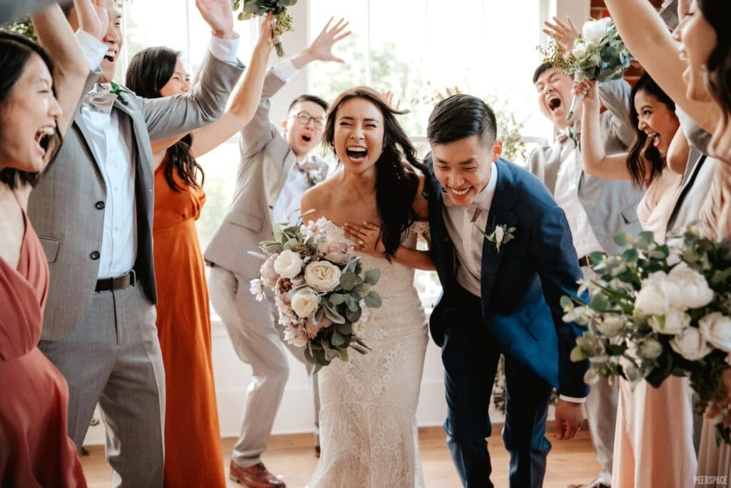 A couple laughs gleefully as they walk through cheering friends and family after tying the knot