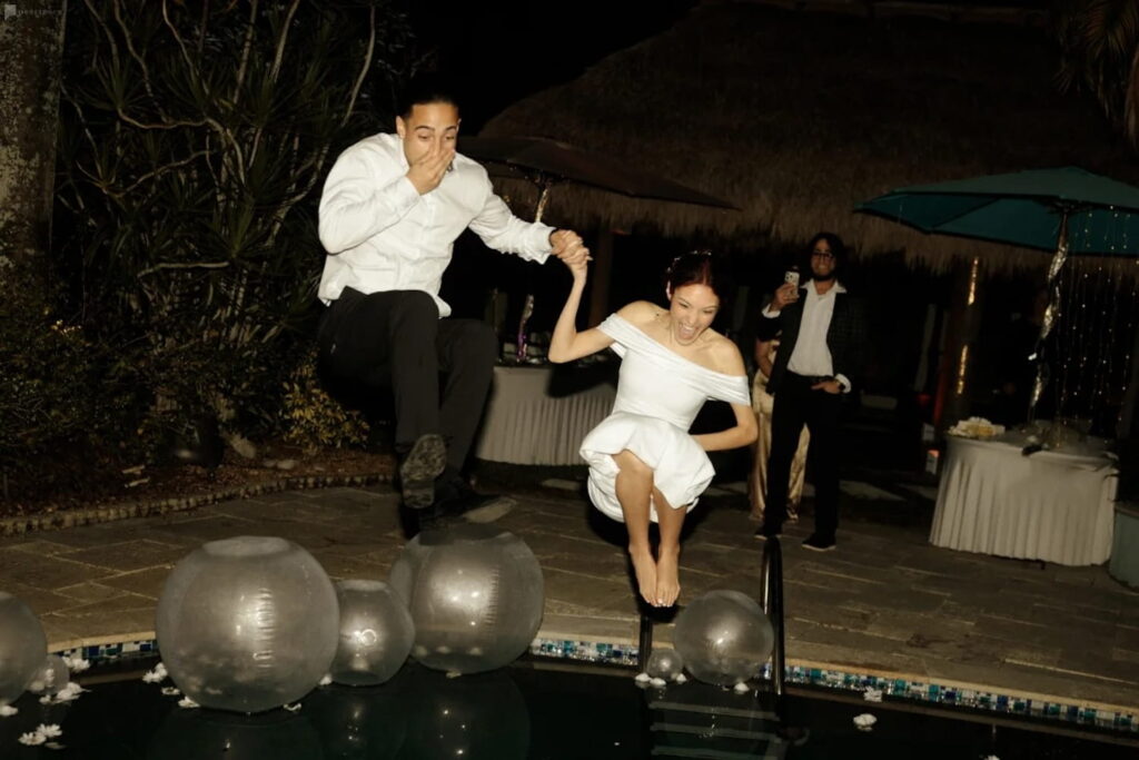 Joyful bride and groom leaping into a pool