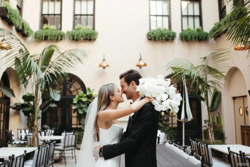A newly wedded couple kisses in courtyard