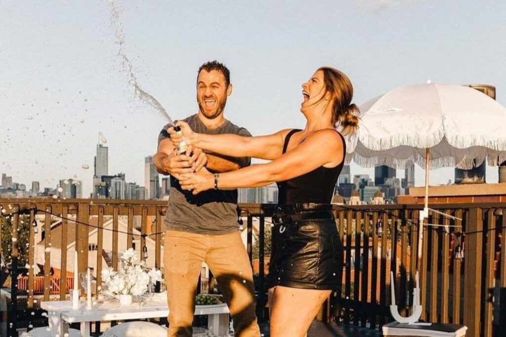 couple popping champagne on a rooftop