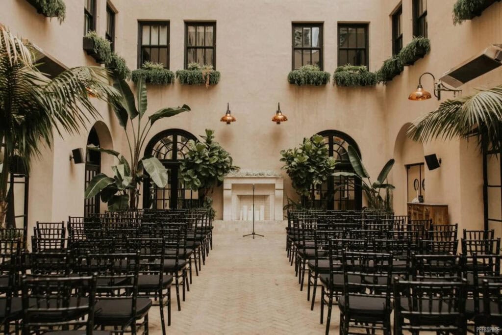 Lush greenery decorates outdoor courtyard set up for wedding ceremony