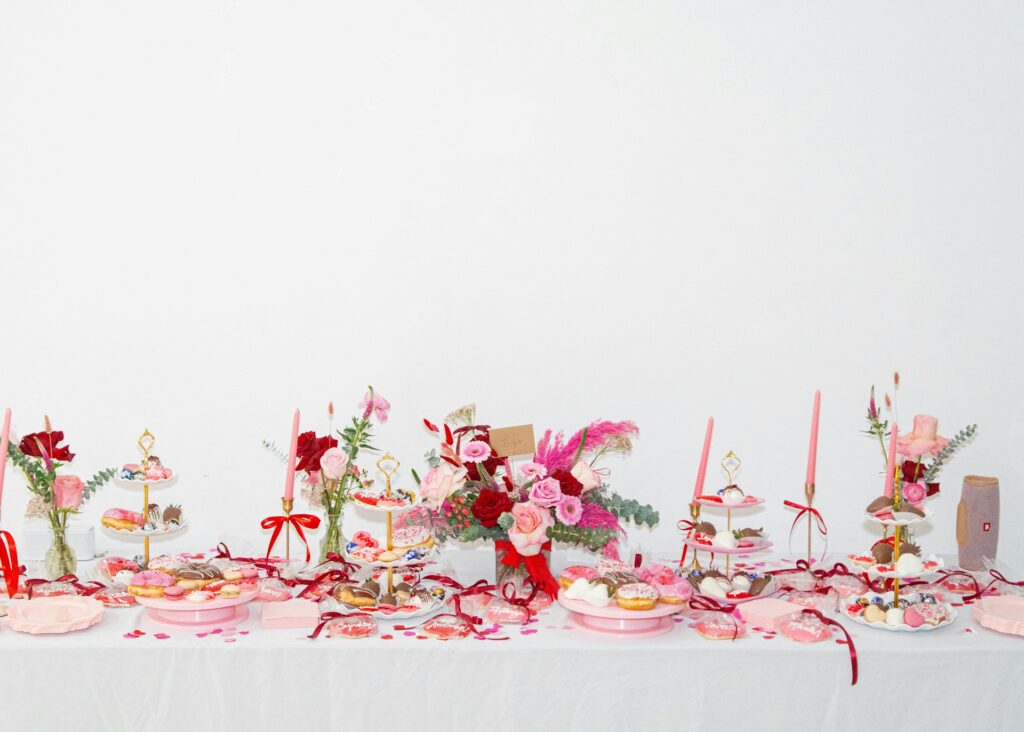 Galentines party table decorated with food, flowers, candles