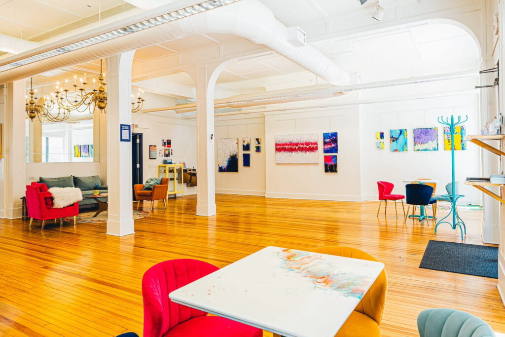 Brightly colored furniture and art decorates a bright, white event space with shiny wood floors